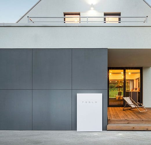 A Tesla solar battery installed on the exterior wall of a home, part of a comprehensive solar power system