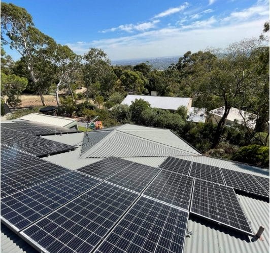 Rooftop solar panels installed on a home, showcasing a complete solar power system with inverters and a battery storage unit.