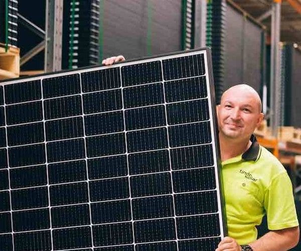 Man holding solar panels supplied by a solar wholesaler, showcasing high-quality solar products for efficient energy solutions
