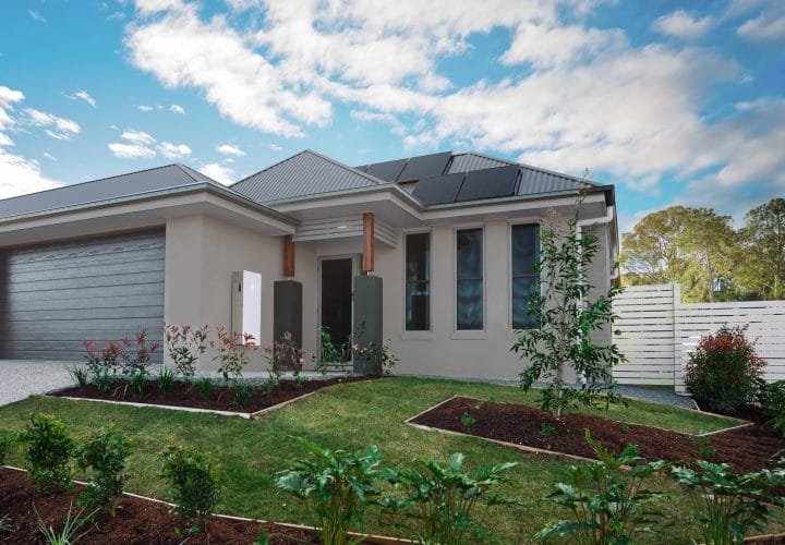 A Tesla Powerwall 3 is mounted on the exterior wall of a house, accompanied by a rooftop solar panel system. The Tesla battery stores solar power for backup energy and off-grid living.